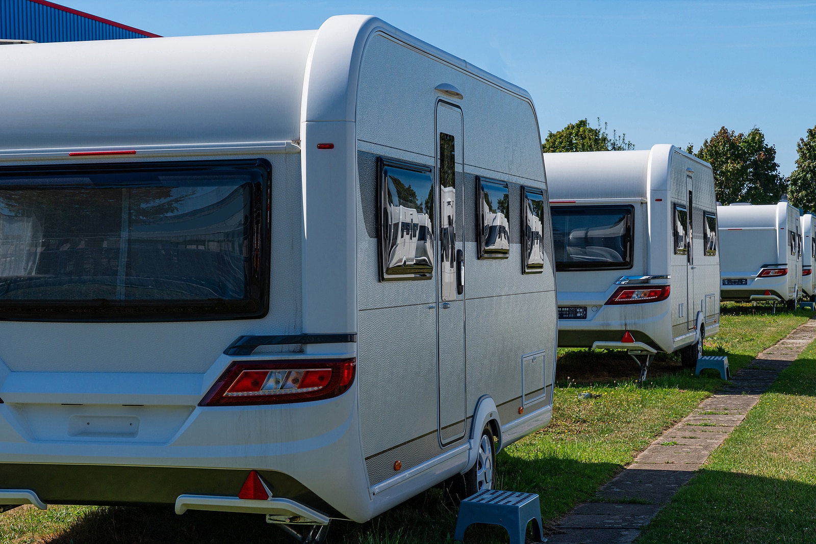 A row of touring caravans on standing on a sunny day in summer with a blue sky.