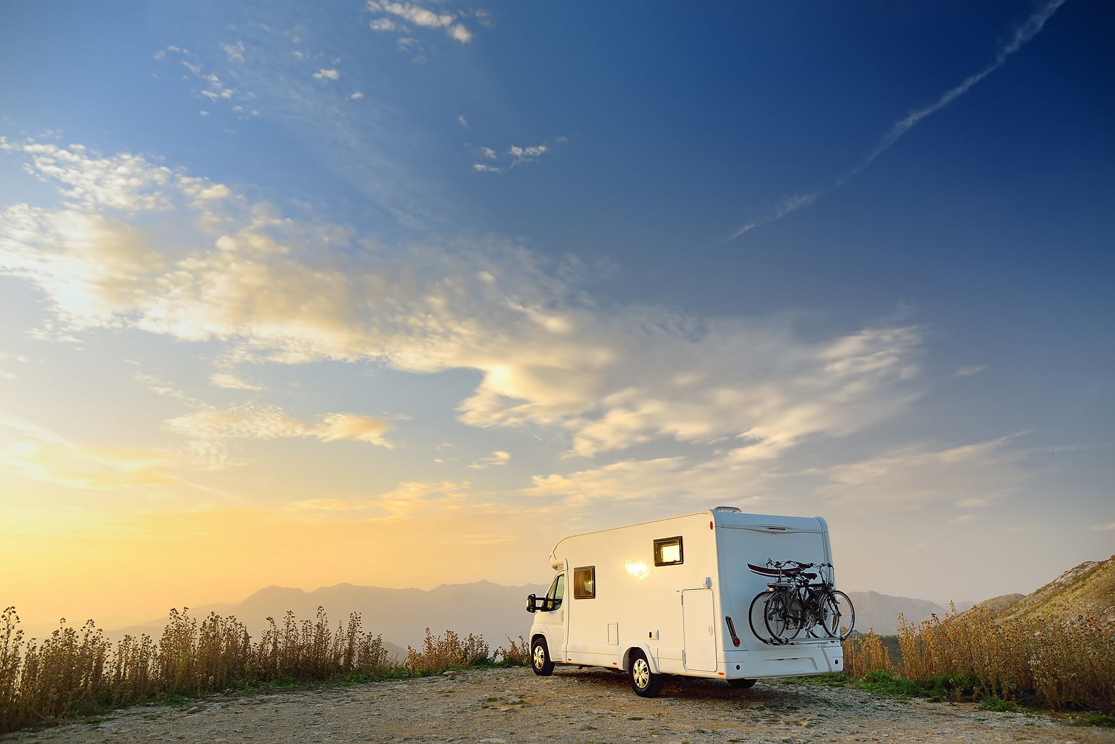 Parked big modern camper motorhome. Family vacation travel RV. Bicycles attached to a caravan. Travel and adventure. Go everywhere concept.